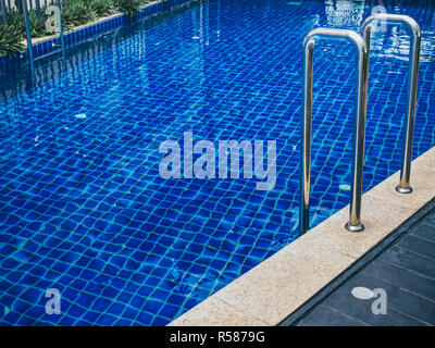 Grab bars ladder in swimming pool. Swimming pool stairs with copy space. Stock Photo