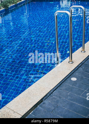 Grab bars ladder in swimming pool vertical style. Swimming pool stairs with copy space. Stock Photo