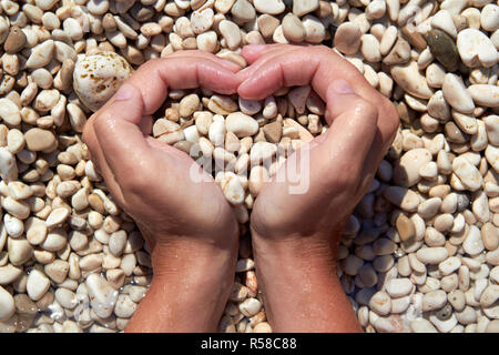 Hands in the form of heart with pebbles inside Stock Photo