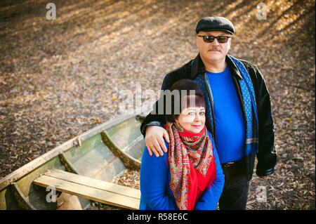 adult couple walking in autumn park. husband and wife walking outdoors in autumn last days, man with a mustache wearing sunglasses Stock Photo