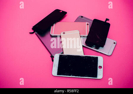 Broken mobile phone lies on a pink background. Stock Photo
