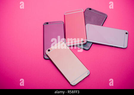 Broken mobile phone lies on a pink background. Stock Photo