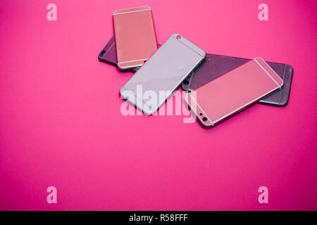 Broken mobile phone lies on a pink background. Stock Photo