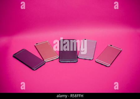 Broken mobile phone lies on a pink background. Stock Photo