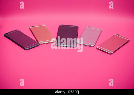 Broken mobile phone lies on a pink background. Stock Photo