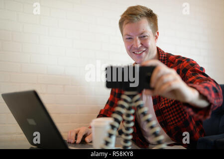 Young Happy Hipster Man Vlogger Fixing Phone At The Coffee Shop Stock Photo