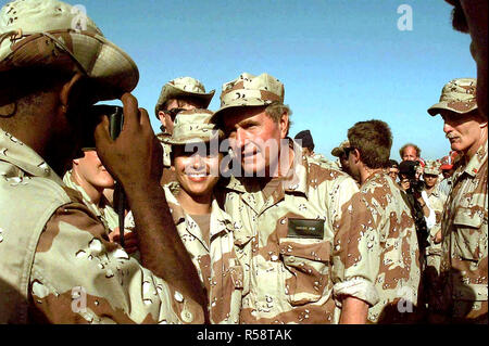1993 - Medium close-up of US President Bush taking tome to pose for a picture with an unidentified female member of the US Forces assigned to the mission in Somalia.  A large number of other members of the force have gathered around the President.  The President visited Somalia to show is gratitude to those involved in the mission of Operation Restore Hope.