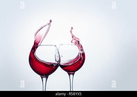 Two wine glasses in toasting gesture with big splashing. Stock Photo