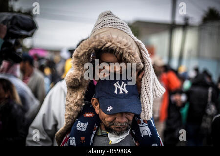 Tijuana, Mexico. 29th Nov, 2018. A father and his daughter are waiting to be taken to another shelter. More than 6000 Central American migrants on the US border move to larger accommodation. The previous migrant accommodation in a sports facility was only designed for 3000 people and was overcrowded. Credit: Omar Martínez/dpa/Alamy Live News Stock Photo