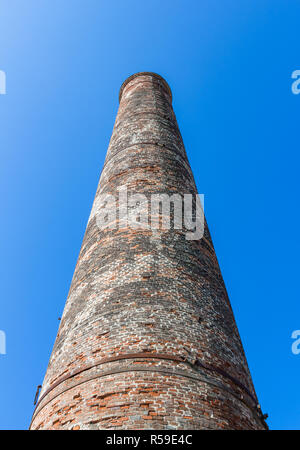 Bottom view of the old brick chimney isolated on a blue sky background. Stock Photo