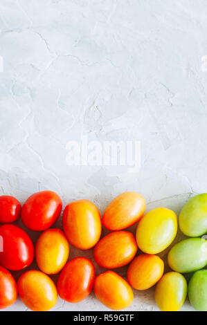 Bright colorful tomatoes on a white stone background. Overhead v Stock Photo