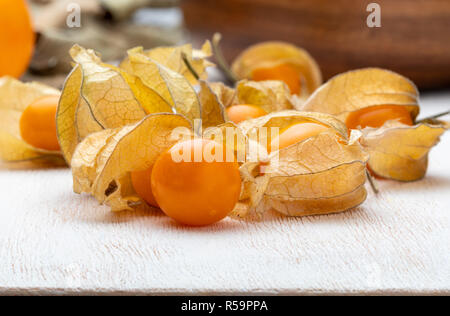 Flowers and fruits of Fisalis (Physalis peruviana). On light colored wooden background. Stock Photo
