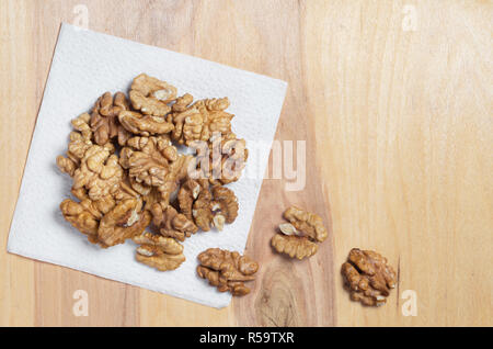 Heap of walnuts kernels on napkin is located on a wooden background, top view with copy space Stock Photo