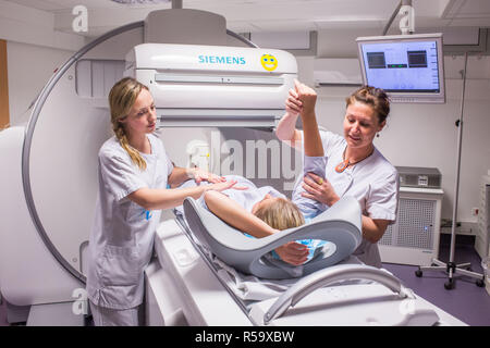 Scintigraphy using a gamma camera coupled to a scanner, Installation of the patient by radiology technicians, Angouleme hospital, France. Stock Photo