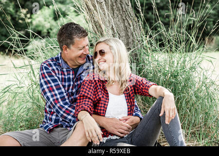 young smiling woman with his happy boyfriend sitting on the meadow Stock Photo