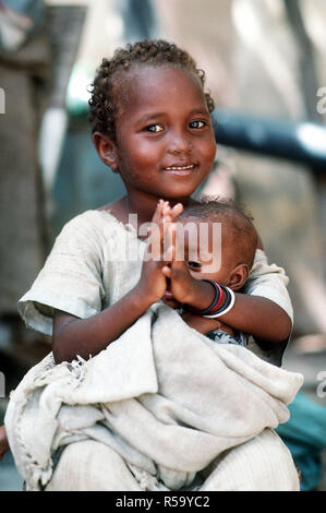 A Somali girl holding an infant waits to be examined by a Navy corpsman.  Combat Service Support Detachment 15 (CSSD-15) is conducting a medical civic action program during the multinational relief effort Operation Restore Hope.