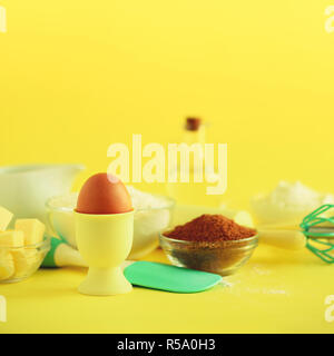 Bakery food frame, cooking concept. Different baking ingredients - butter, sugar, flour, milk, eggs, oil, spoon, rolling pin, brush, whisk over yellow Stock Photo