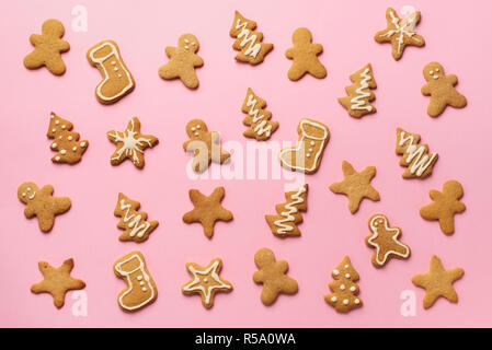 Homemade christmas cookies on pink background. Pattern of gingerbread men, snowflake, star, fir-tree, boot shapes. New year concept. Stock Photo
