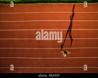 Shot of a young male athlete training on a race track. Sprinter running on athletics tracks seen from above. Stock Photo