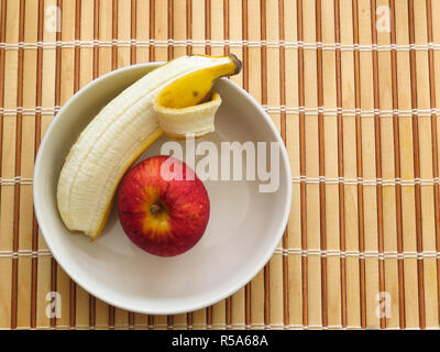 Apple and banana inside bowl on wooden table Stock Photo