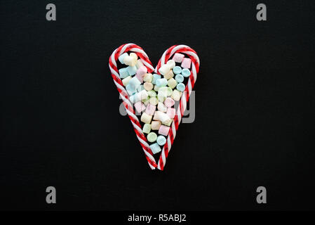 Heart made from candy canes with marshmallows on blackboard Stock Photo