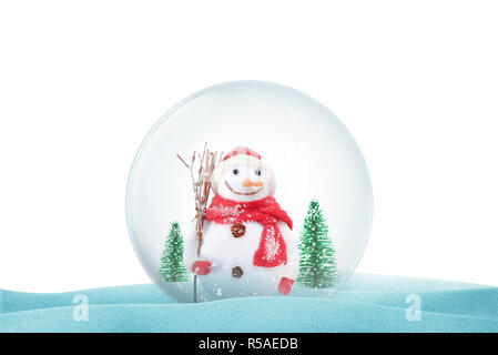 Isolated Christmas magic ball on snow with snowman and trees. Christmas decorative ball with snow falling. Stock Photo