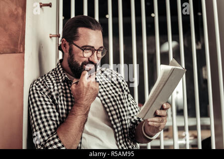 So busy schedule. Nice thoughtful man looking at his notes while studying them carefully Stock Photo