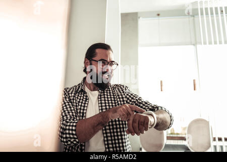 New device. Delighted nice man using his modern watch while setting the time Stock Photo