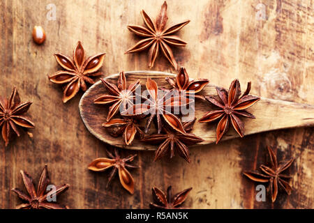 Anise stars on wood spoon close-up. Anason, anise star over wood background. Stock Photo