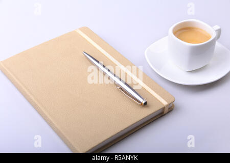 stylish notebook, ballpoint pen and white cup with a fragrant espresso coffee on the office desk Stock Photo
