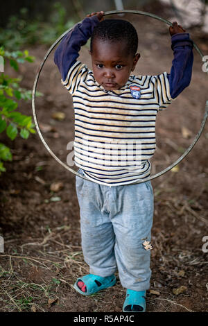 Portrait of an adorable young Tanzanian boy of 3 years old playing  with a hoop in his yard Stock Photo