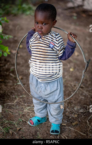 Portrait of an adorable young Tanzanian boy of 3 years old playing  with a hoop in his yard Stock Photo