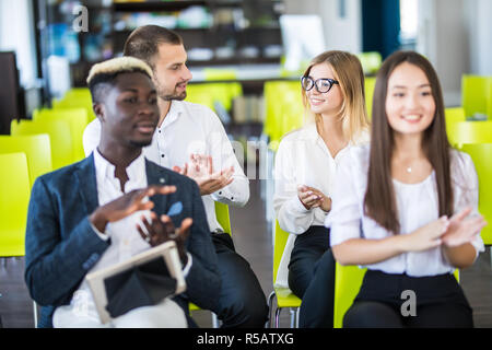 Multi ethnic business group greets somebody with clapping and smiling Stock Photo