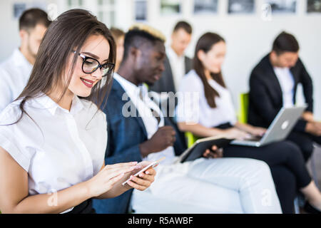 Diverse office people working on mobile phones, corporate employees holding smartphones at meeting, serious multiracial businessmen and businesswomen  Stock Photo