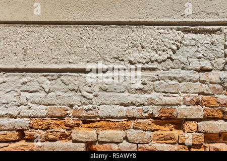 Detail view of an old brick wall with broken surface area of plaster. Stock Photo