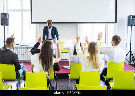 Group of business people raise hands up to agree with speaker in the meeting room seminar Stock Photo