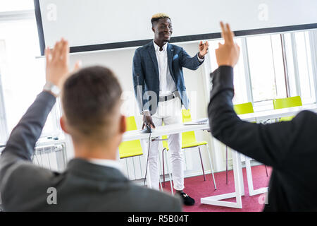 African american businessman giving presentation discussing project with multi-ethnic group at corporate training, black teaching coach answering ques Stock Photo