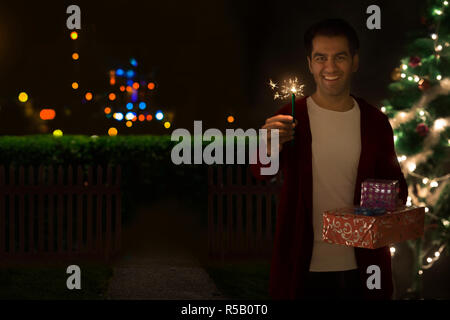 Man holding a present and a star shaped sparkler Stock Photo