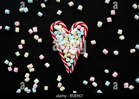 Heart made from candy canes with marshmallows on blackboard Stock Photo
