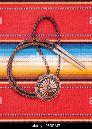 Vintage Sterling Silver Bolo Tie with Concho and Silver Tips on colorful southwestern hand woven fabric. Stock Photo