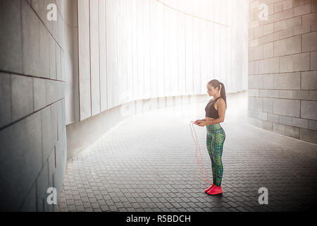 Serious and concentrated young woman stands in middle of tonnel and looks at rope she had in hands. Nodel has rest. She is calm amd peaceful Stock Photo