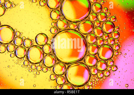 Abstract background of close up detail in vegetable oil droplets/bubbles on the surface of water with a colourful background