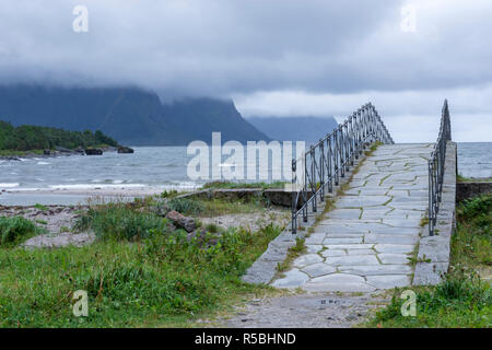 Beautiful stone bridge down to the beach in foreground and a stormy sea with low clouds in background, picture from Northern Norway. Stock Photo