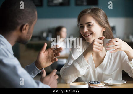 Happy young diverse couple enjoy coffee having fun meeting in cafe, multiethnic millennial boyfriend and girlfriend laugh spending time together in co Stock Photo