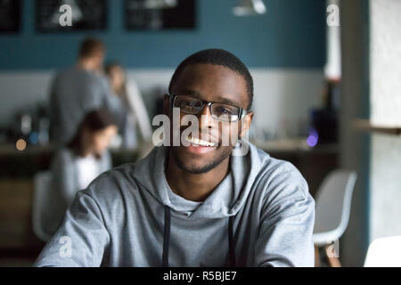 Portrait of smiling African American student looking at camera sitting in cafe, black millennial man posing making picture in coffeeshop, afro male in Stock Photo