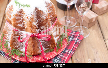 Traditional Italian Christmas fruit cake Panettone Pandoro with festive red ribbon and Christmas decorations. On a wooden background. Free space for t Stock Photo
