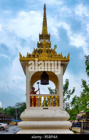 Monk ringing a bell in Wat Mongkhon Nimit, Phuket Town, Thailand Stock Photo