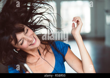 Playful woman listening to music with smartphone.