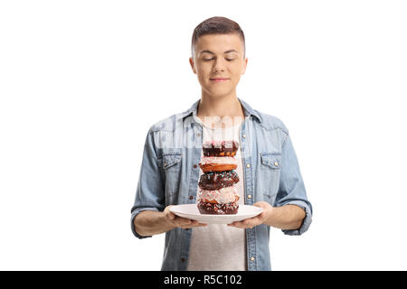 Teenage boy holding a plate of donuts and looking at it isolated on white background Stock Photo