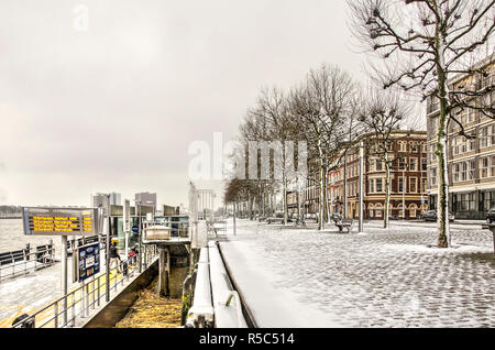 Rotterdam, The Netherlands, December 11, 2017: Willemskade quay and the waterbus stop covered with a thin layer of snow on a cold winter day by the Ni Stock Photo